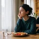Yemek masasında dalgın oturan ergen, ergenlerde bulimia ve yeme bozukluğu işaretleri